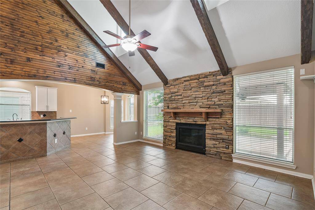 Stunning family room with soaring vaulted ceilings, rich wood beams, and a dramatic custom stone fireplace—creating a warm and inviting space perfect for relaxing or entertaining.