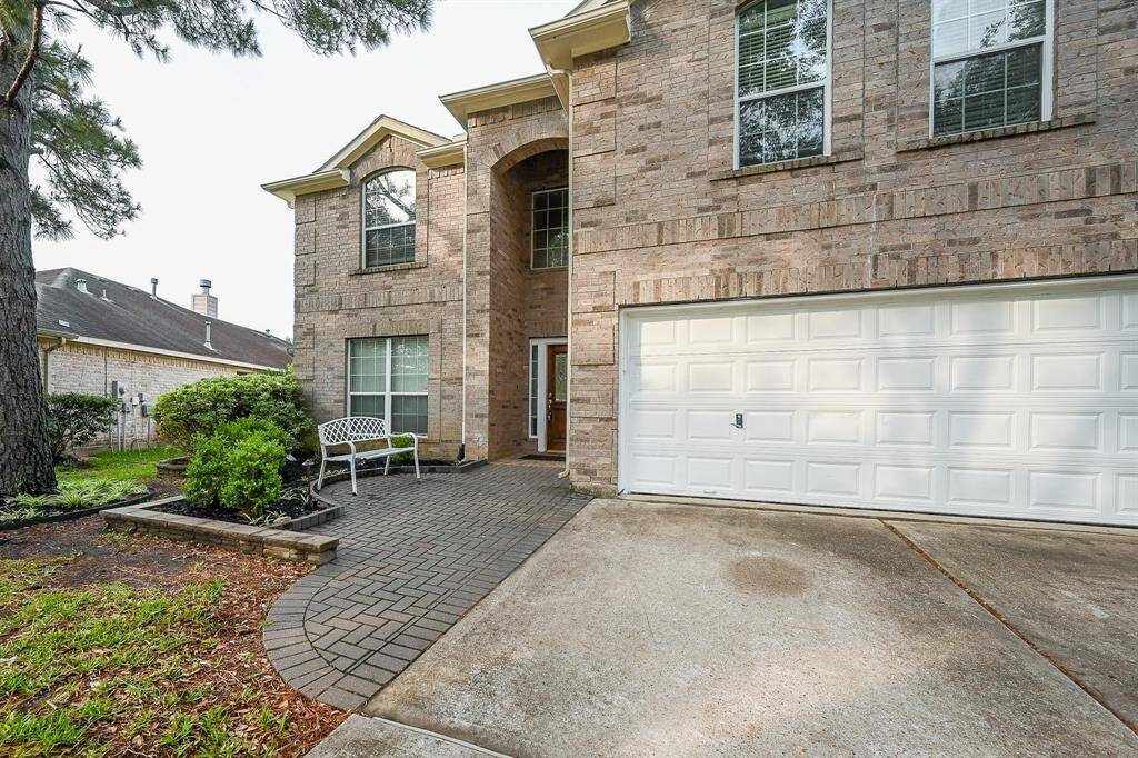 There's a paved walkway leading to the door, flanked by a small garden area with shrubs and a bench, offering a cozy outdoor space.