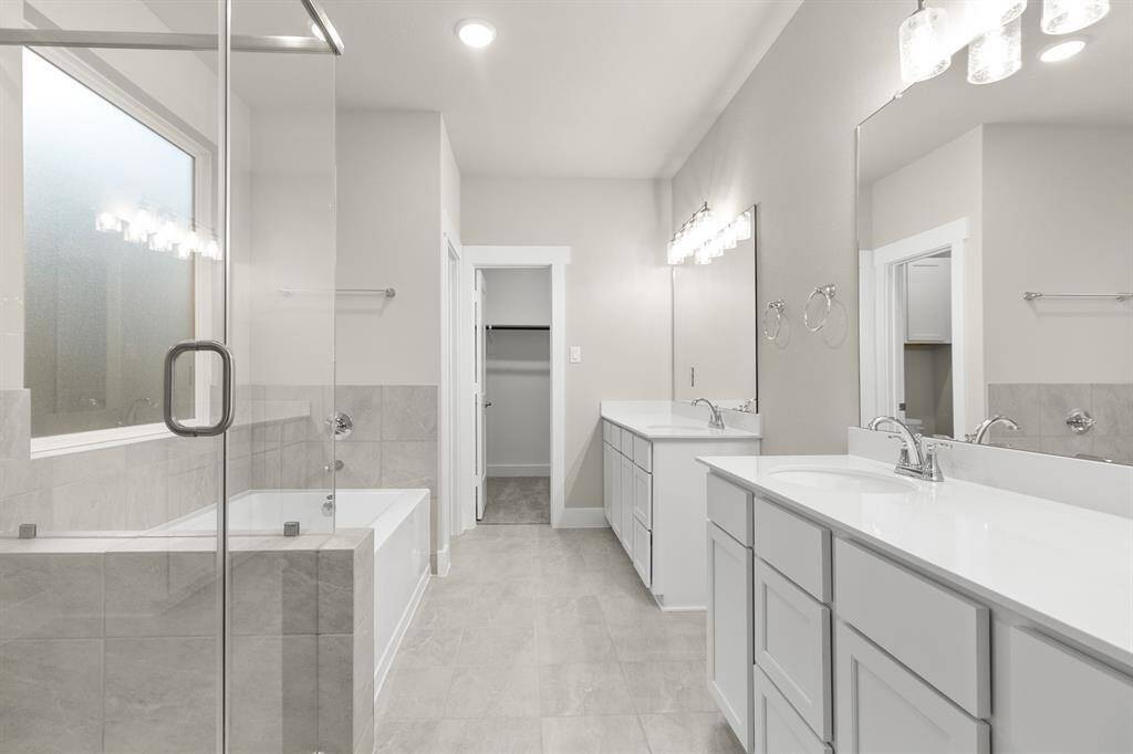 The primary bathroom is a serene retreat, with a split double vanity offering separate his-and-hers spaces, each with its own sink, mirror, and plenty of counter room for daily routines.
