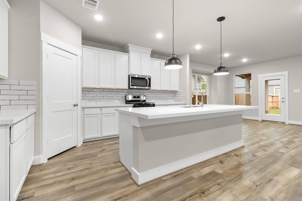 A pristine white quartz countertop stretches across the large island and surrounding surfaces, offering both elegance and durability.
