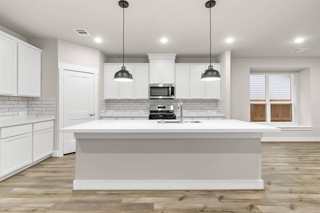 The open concept kitchen is bathed in natural light, highlighting the sleek white cabinets that lend a modern, sophisticated feel to the space.