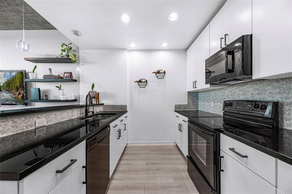A contemporary kitchen with a sleek, polished vibe, featuring bold black appliances that contrast beautifully against light cabinetry and neutral walls.