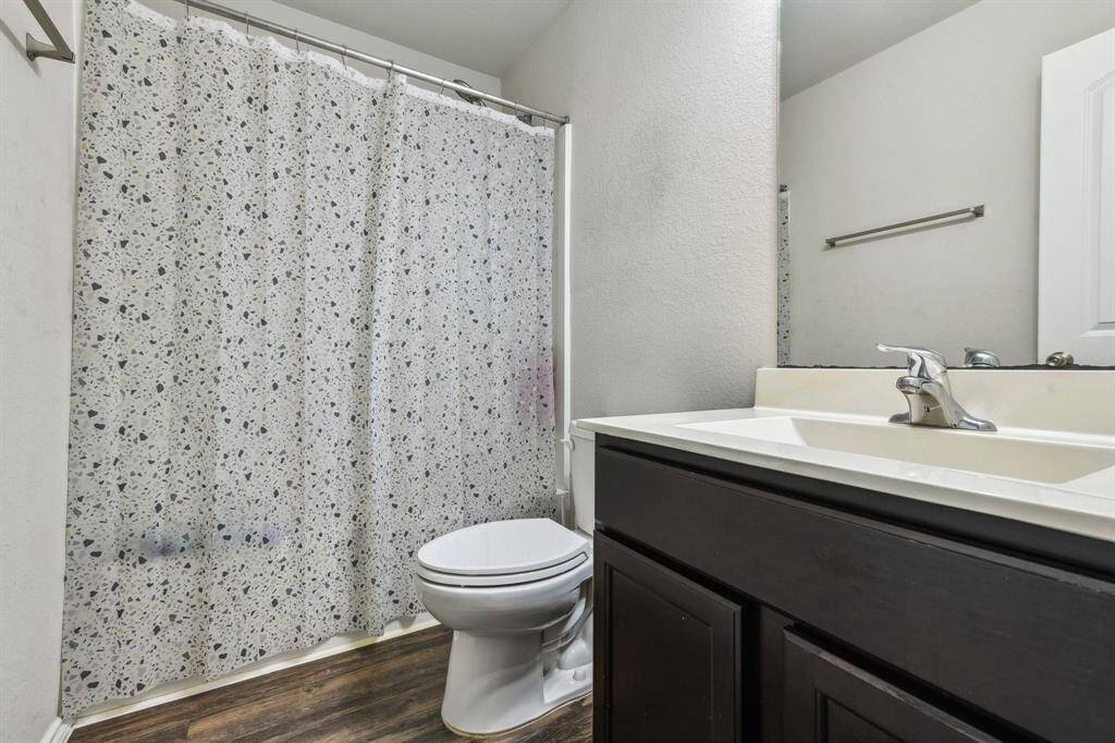 This bathroom features a modern vanity with a sleek faucet and neutral walls. The flooring is dark wood, adding a touch of elegance.