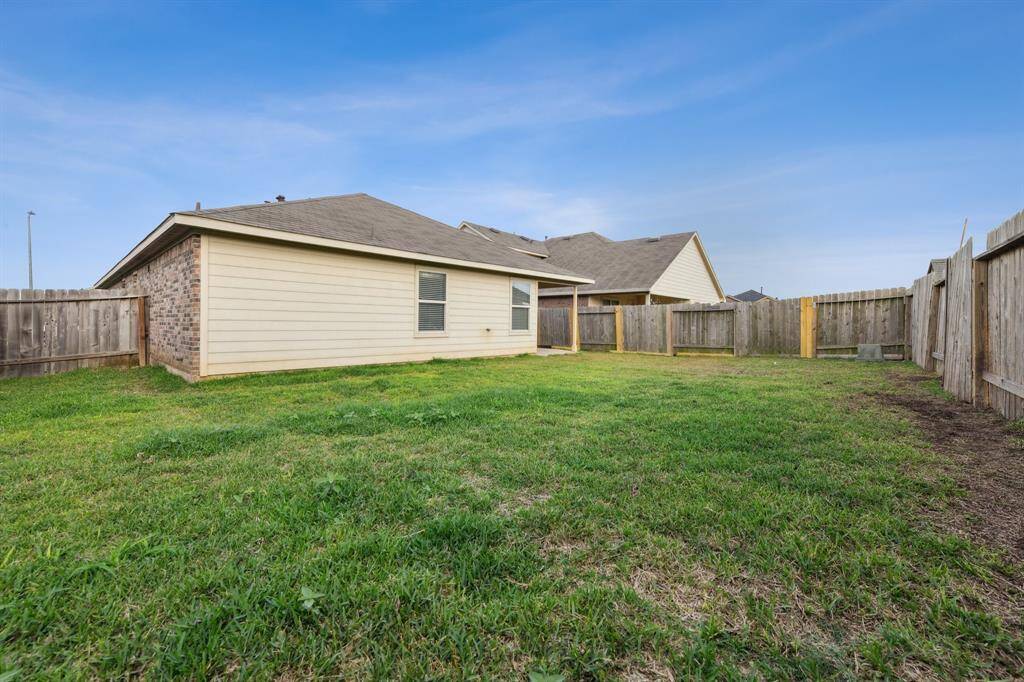 Spacious fenced backyard with well-maintained grass, perfect for outdoor activities and privacy. The exterior features a mix of brick and siding.