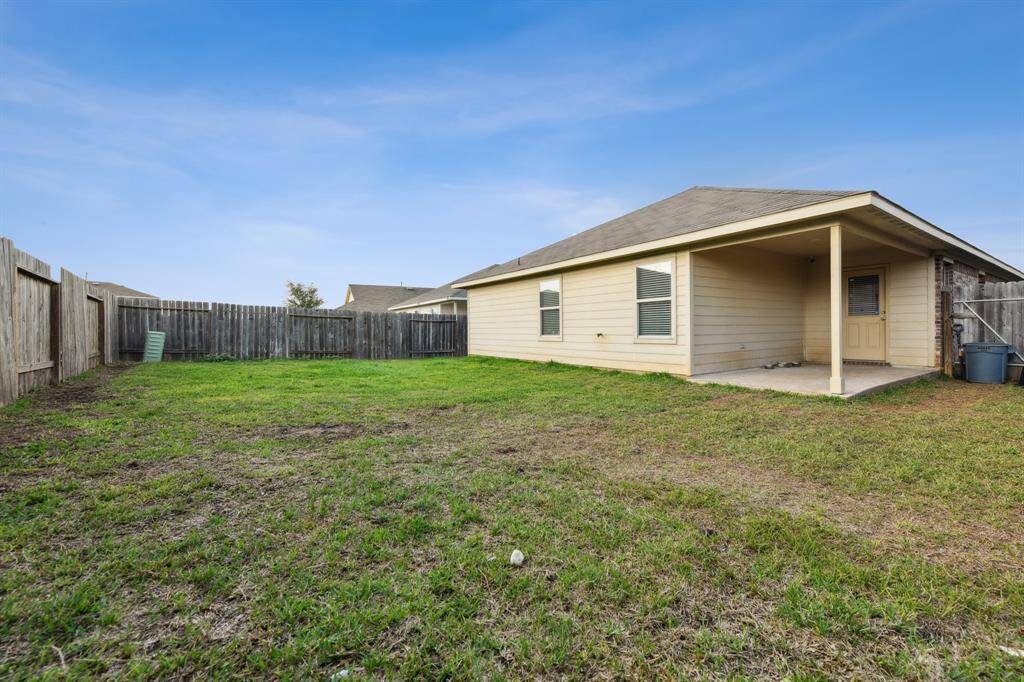 Spacious fenced backyard with a covered patio, perfect for outdoor activities and relaxation.