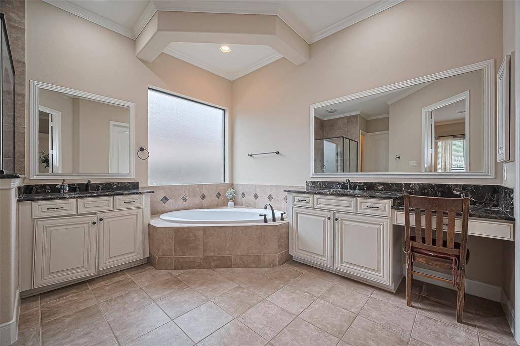 Elegant owner’s bath with separate shower and tub, double vanity, and dual walk-in closets for ultimate comfort.