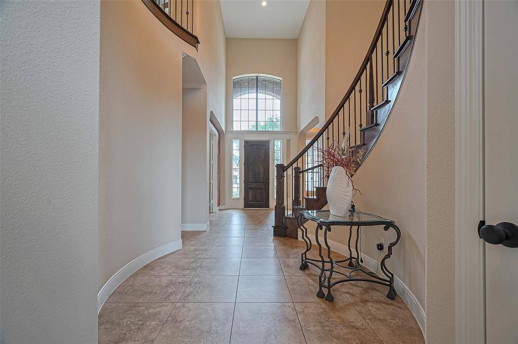 The entry hallway features soaring ceilings and seamlessly connects the home office, formal dining, and living areas.