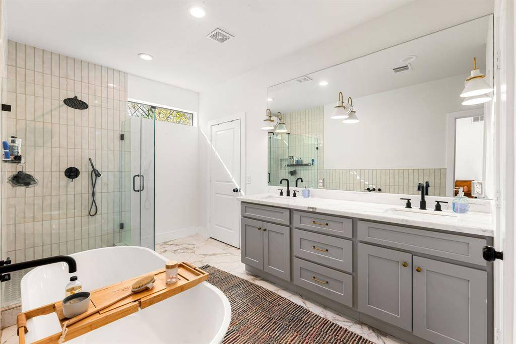 This primary bathroom is definitely move-in ready! Featuring a beautiful walk-in shower with tile surround, separate garden tub for soaking after a long day with custom tile detailing, dark stained cabinets with light countertops, spacious walk-in closet with shelving, high ceilings, custom paint, sleek and dark modern finishes.