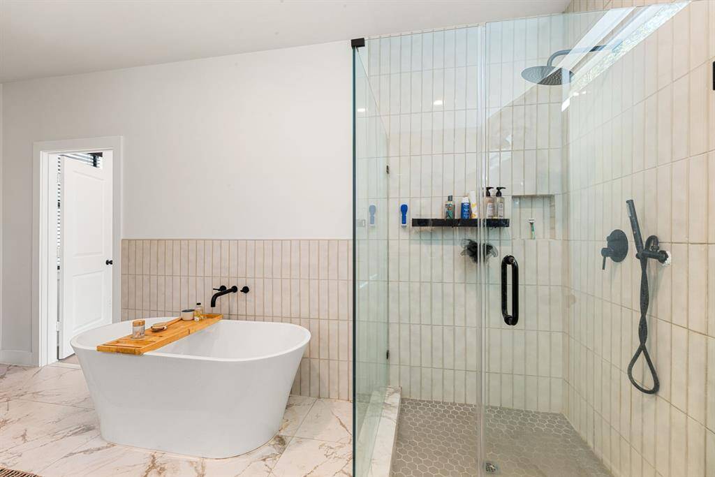 This additional view of the primary bath showcases a walk-in shower with tile surround and a separate garden tub perfect for soaking after a long day.