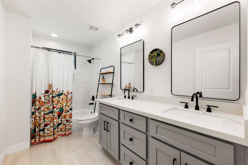 Secondary bathroom features light countertops and cabinets, custom paint, shower/tub combo with tile surround, large mirror, tile floors, sleek fixtures and modern finishes, plenty of space to accommodate any visiting family or guests.