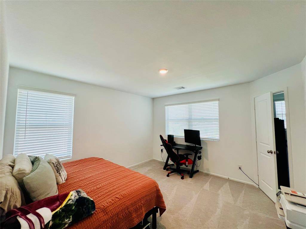 Bright third bedroom with front-facing views, abundant natural light, and a spacious walk-in closet.