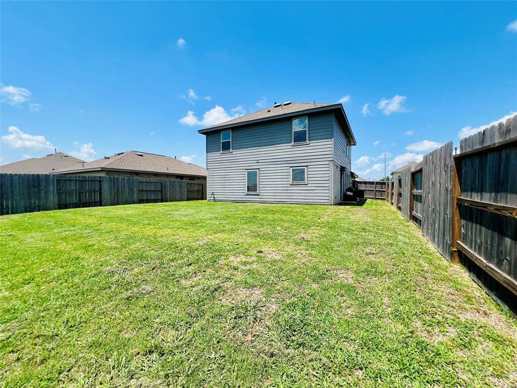Spacious backyard with a well-maintained lawn, enclosed by wooden fencing on the sides and wrought iron on rear of property to enjoy the stunning lake view. The two-story house features a contemporary, modern exterior. Perfect for outdoor activities and privacy.