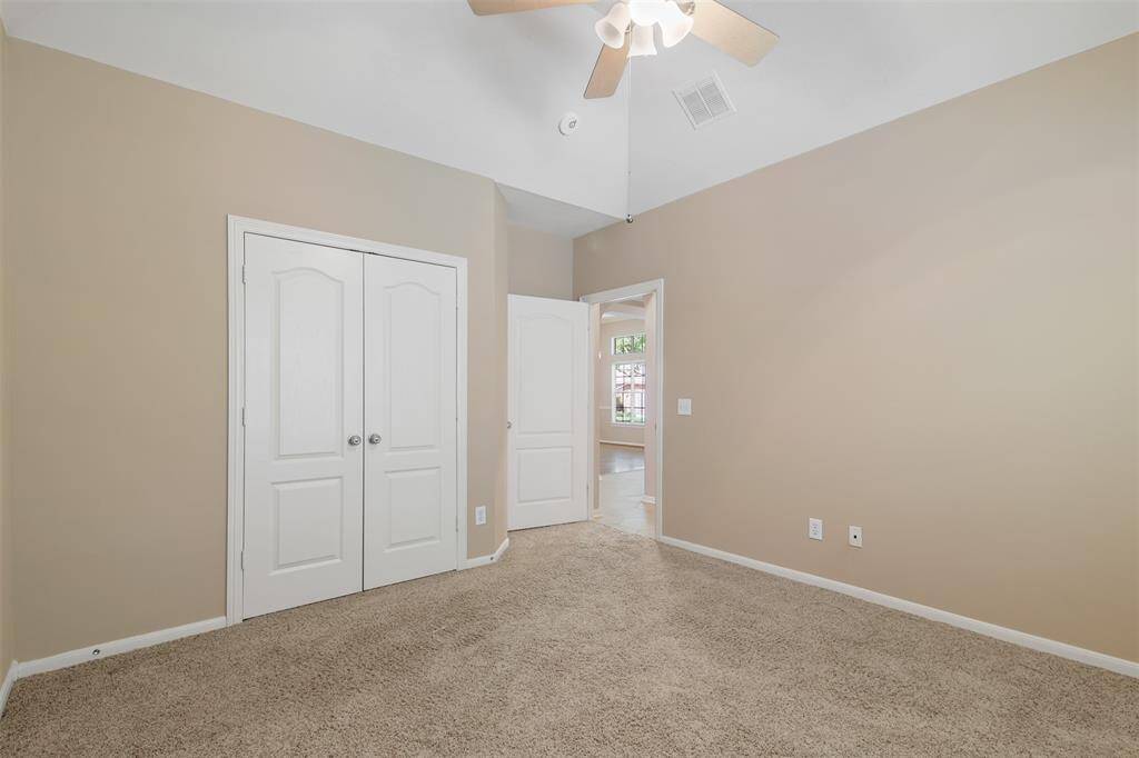 Alternate view of the secondary bedroom with double door closet, carpet and ceiling fan.