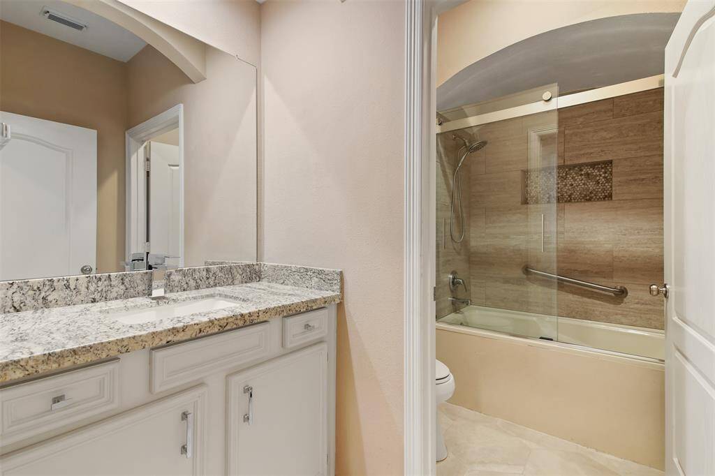 Secondary full bathroom features granite countertops, under mount sink and sliding glass door tub/shower combo.