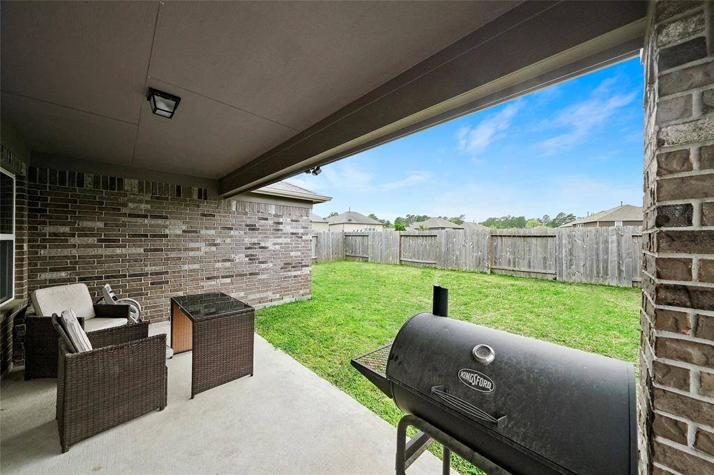 This photo showcases a covered patio with a view of a spacious fenced backyard, perfect for outdoor entertaining.