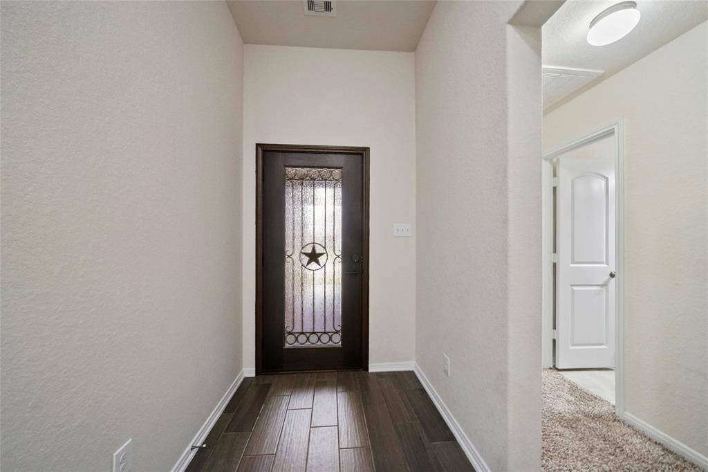 Entry foyer consists of wood-like flooring leading to a decorative glass door featuring a star design. The space is well-lit and has a modern, clean feel.