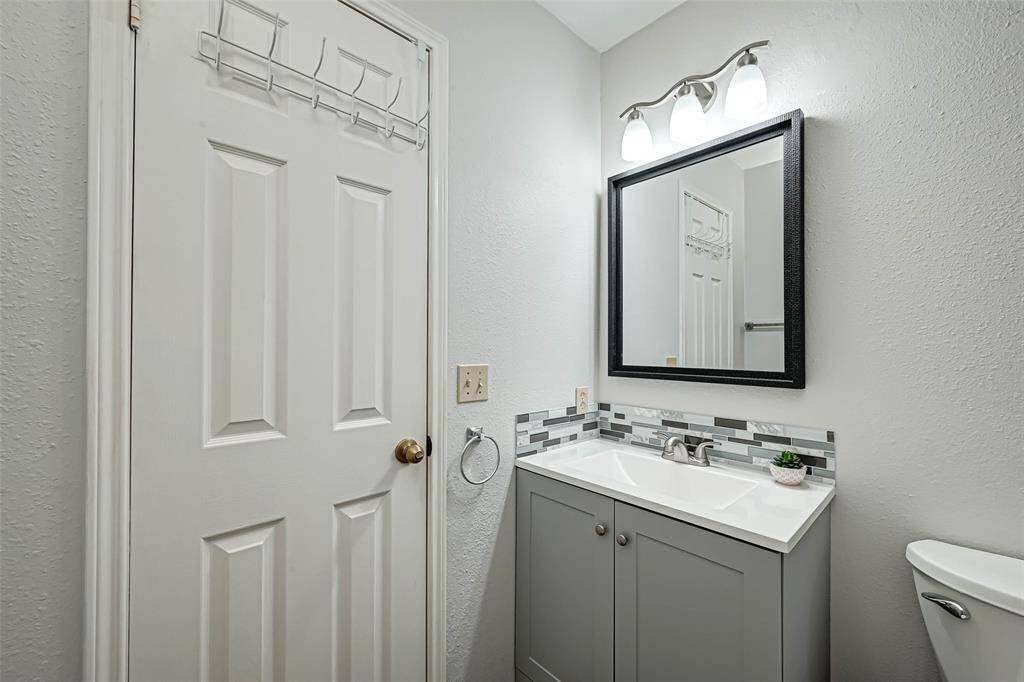 The bathroom has a granite-topped sink and a vanity mirror.