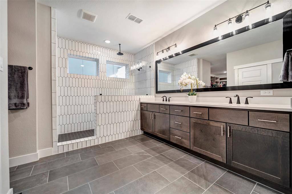 The oversized spa-style primary en-suite features double sinks oversize tiled shower & beautiful cabinets for storage.