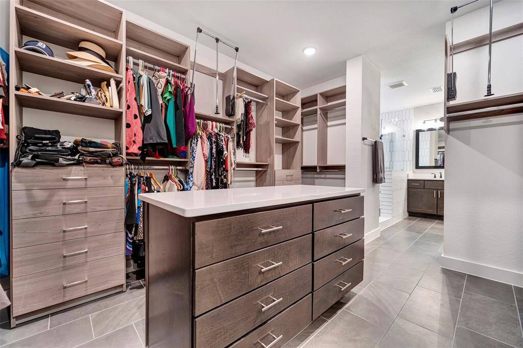 Moving from the en-suite into the primary closet - one of dreams complete with center console finished with a granite countertop.