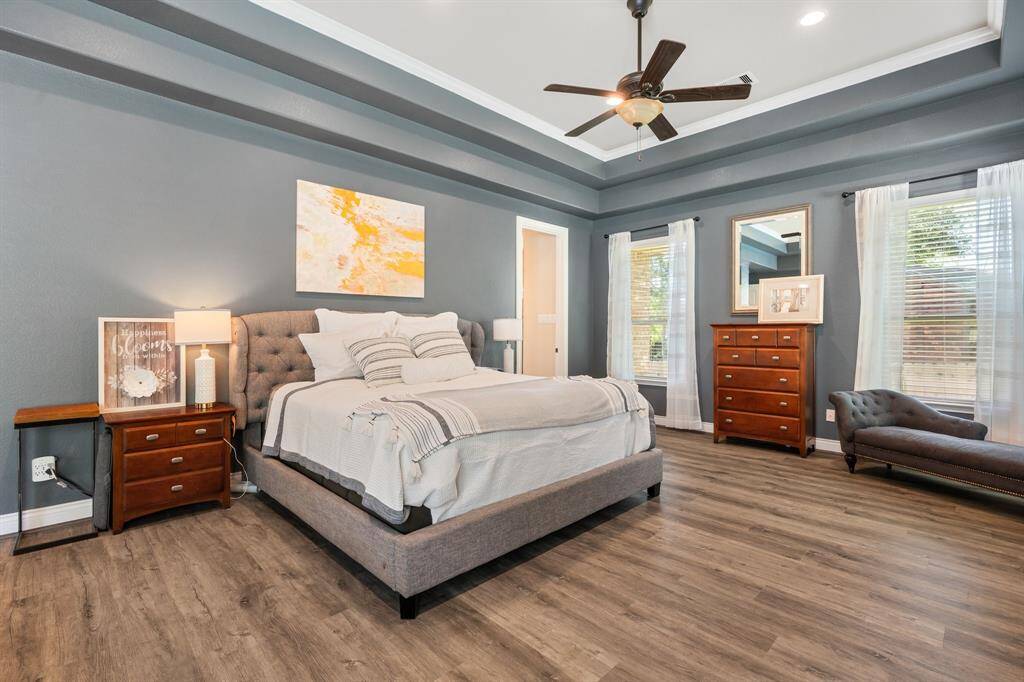 Expansive primary retreat with luxury vinyl plank flooring, tray ceiling, and plenty of windows overlooking the backyard.