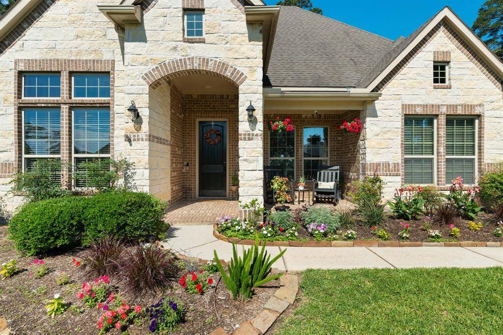 Beautifully manicured flowerbeds.  Covered porch with brick and stone accents.