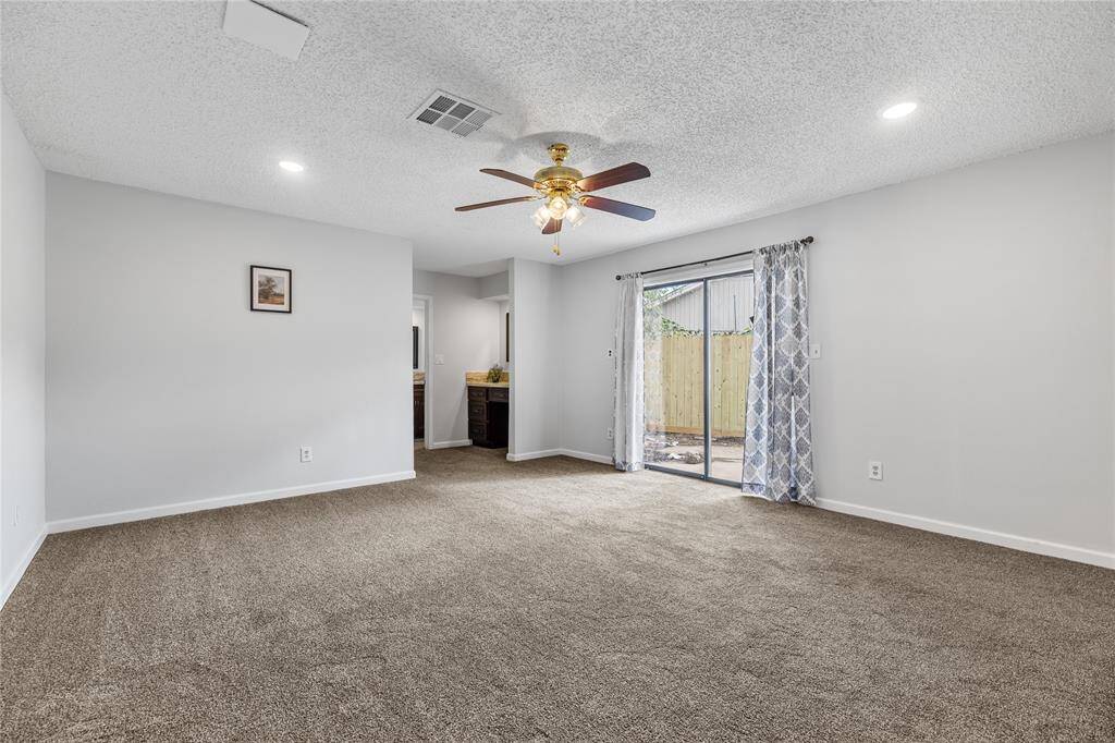 Expansive primary bedroom with direct backyard access through sliding doors.