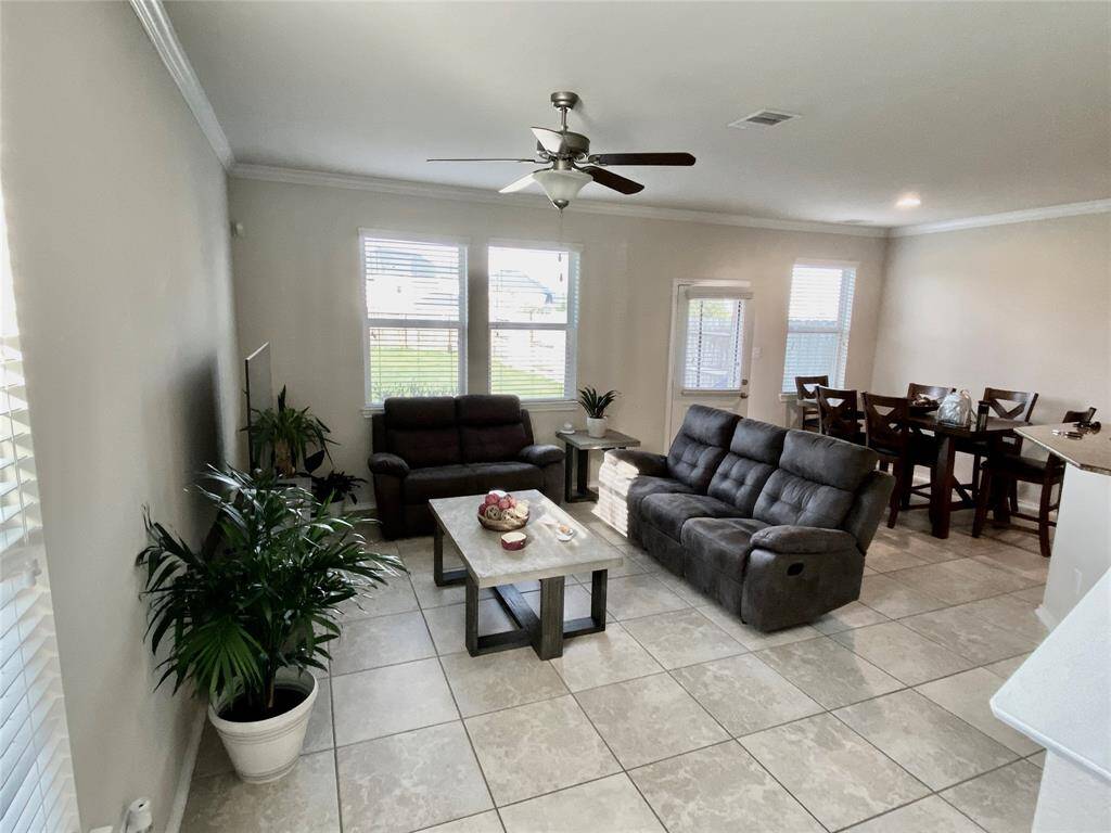 Bright and inviting living room with large windows, modern tile flooring, and an open layout perfect for relaxing and entertaining.