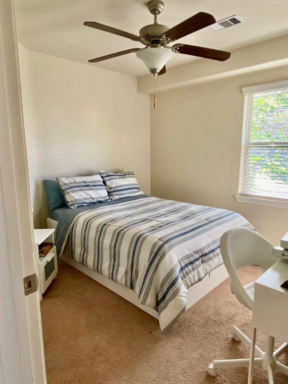 Cozy second bedroom with ample natural light and a ceiling fan for comfort.