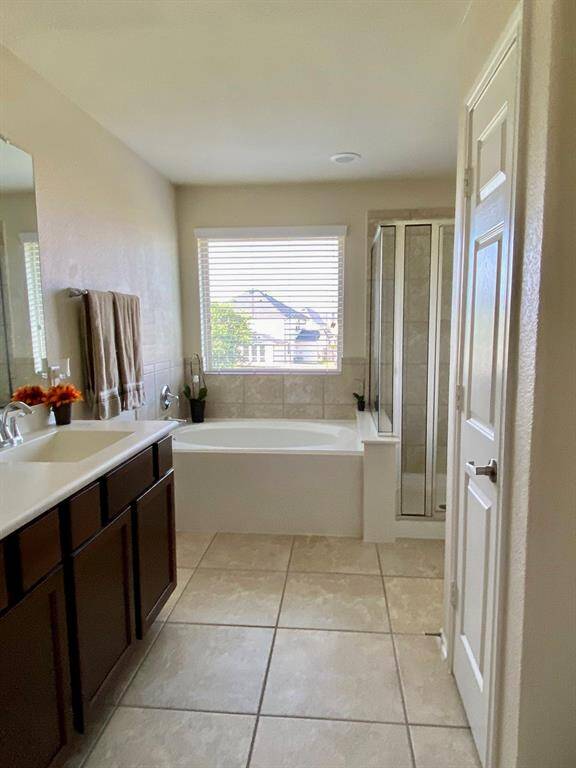 Spacious master bathroom featuring a luxurious soaking tub, separate glass shower, and double vanity for ultimate comfort and style.