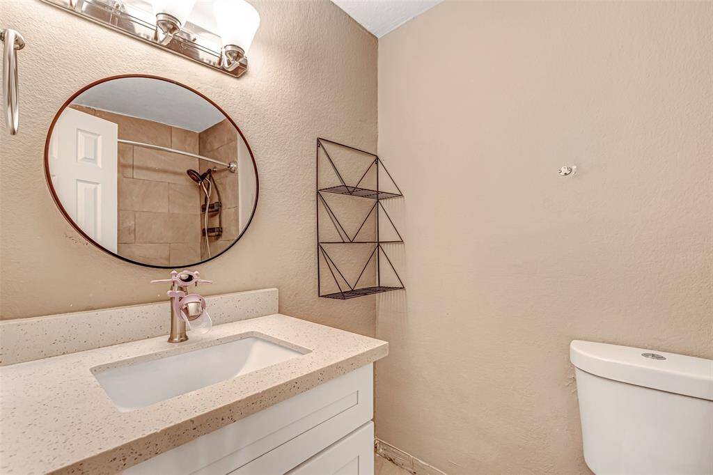 Inviting guest bathroom featuring a modern vanity with a sleek quartz countertop, a stylish round mirror, and elegant lighting.