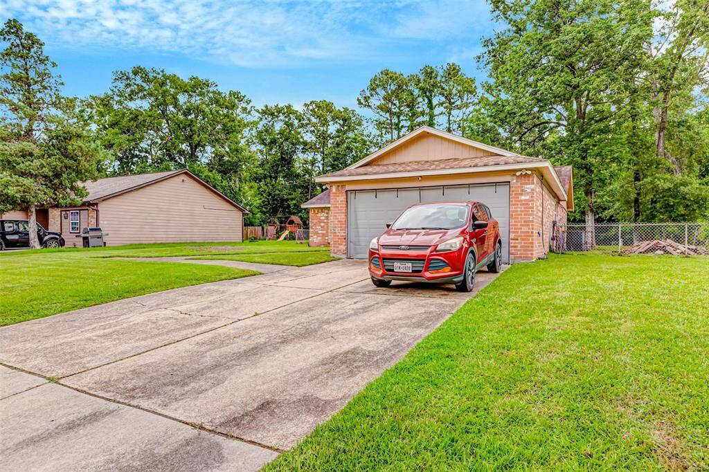 Charming side view of a brick home with a spacious driveway and lush green surroundings. Perfect for family living.