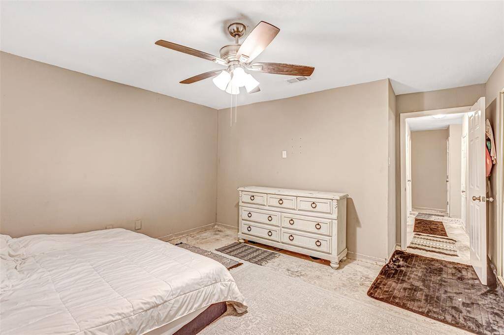 Spacious primary bedroom with a ceiling fan and ample natural light, opening to a cozy hallway.
