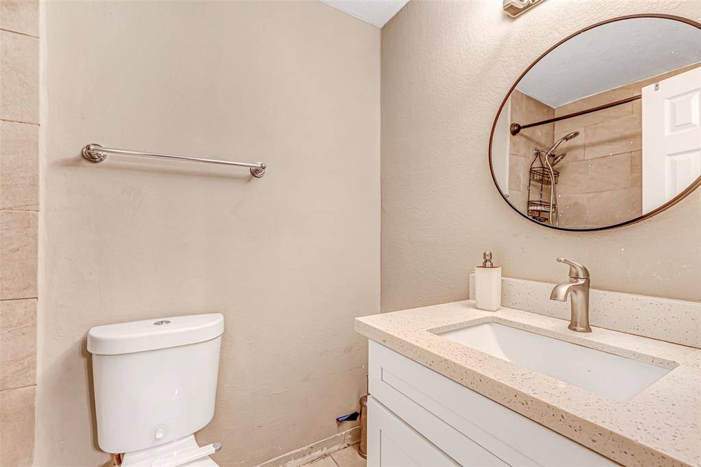 Elegant primary bathroom featuring a sleek vanity with a modern sink, a stylish round mirror, and a convenient shower-tub combo for ultimate relaxation.