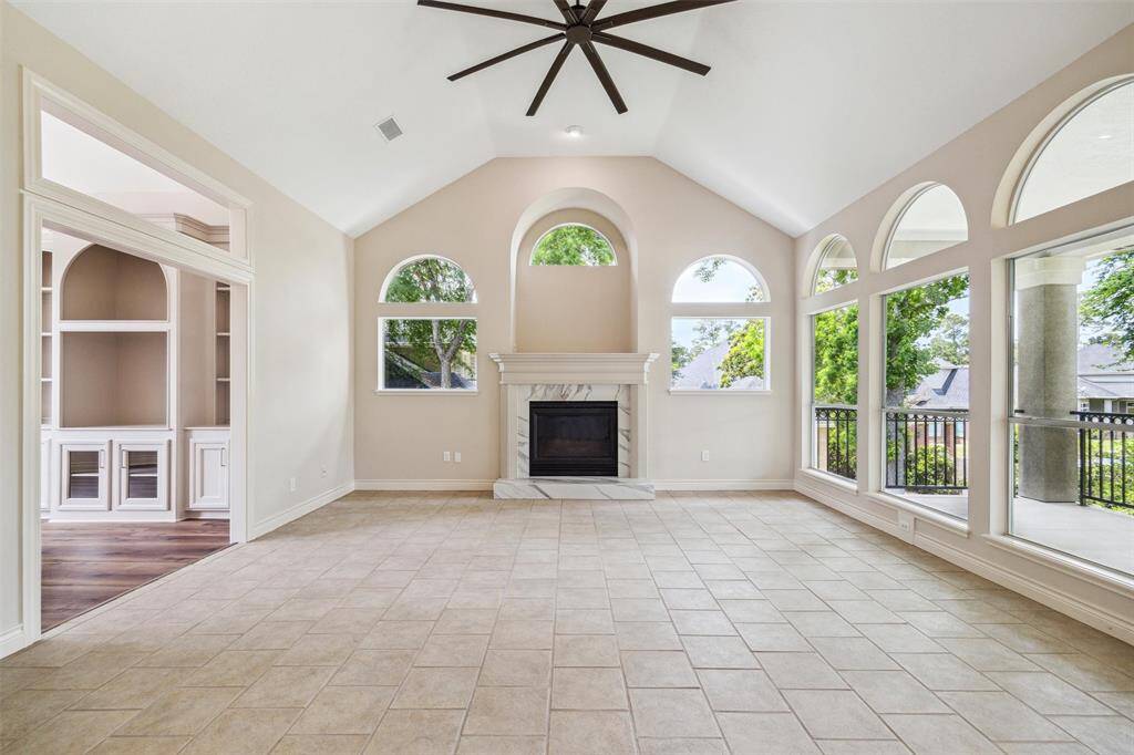 Bright and spacious family room with high vaulted ceilings, a central fireplace, and large arched windows offering plenty of natural light.
