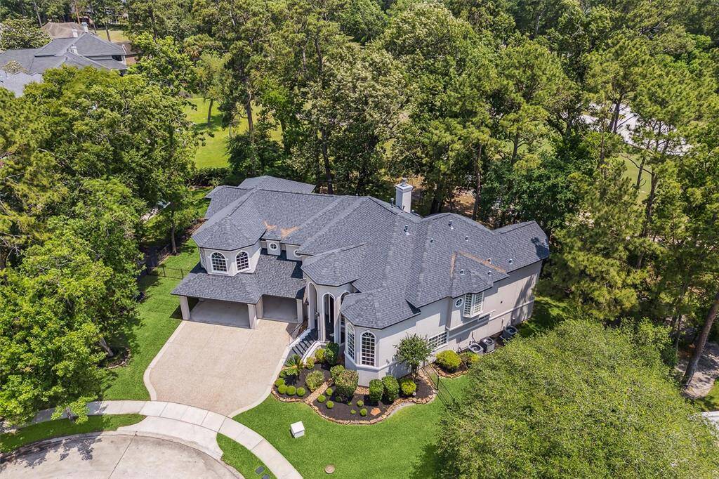 Nestled in a wooded area, offering privacy and lush surroundings. It features a spacious driveway, elegant architectural details, and a beautifully landscaped front yard.