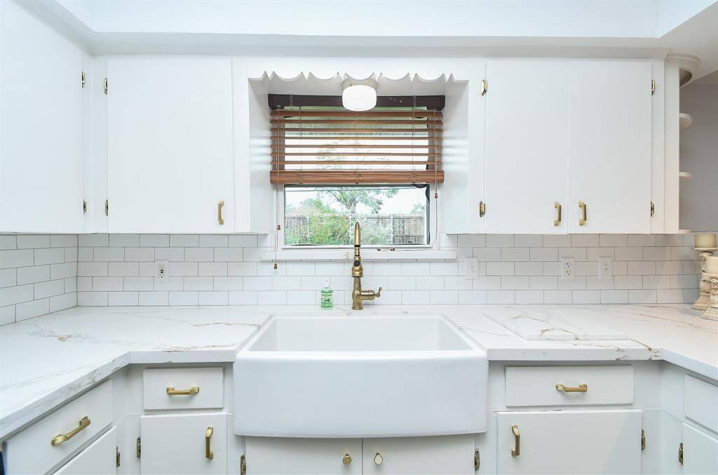 A large welcomed window over the farm house style sink and apron is a beautiful and practical feature, complemented by creamy quartzite counters and good looking, popular subway-style tile backsplash.