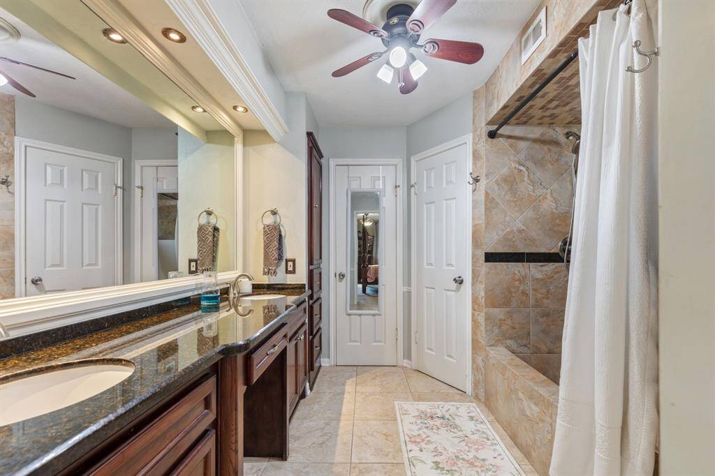 Primary bathroom with dual sinks, granite counters, and large shower
