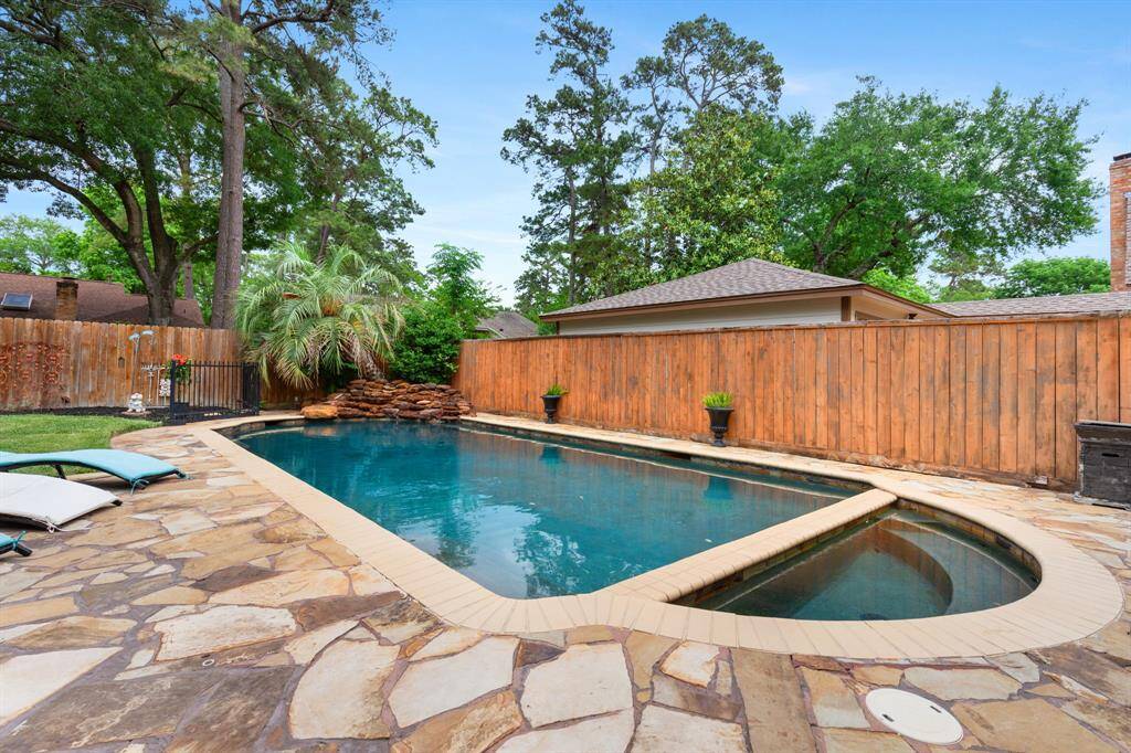 Relax in your backyard oasis with pool, hot tub natural stone decking, and plenty of space to play.