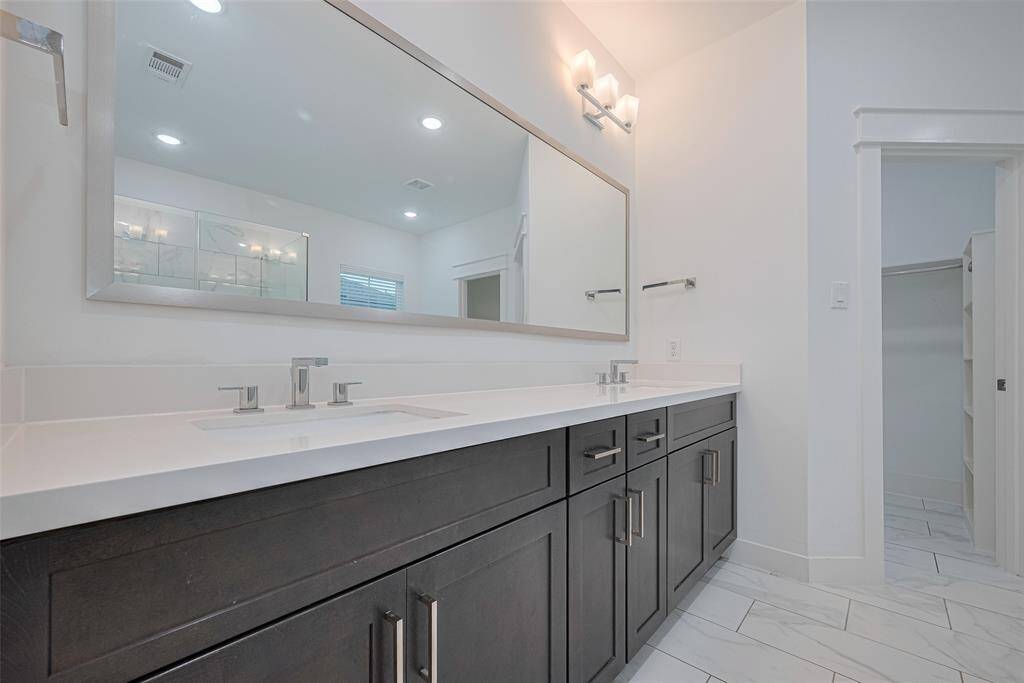 Luxurious primary bathroom offers double sinks, quartz counter and exquisite lighting.