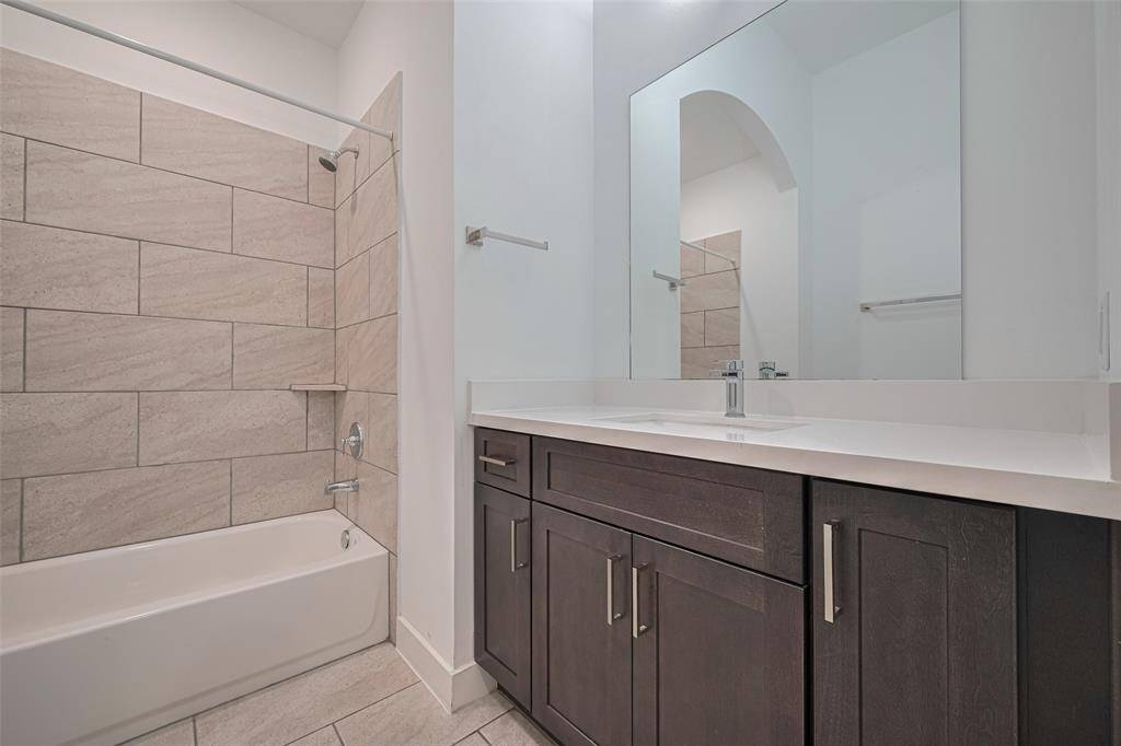 En suite bathroom for the downstairs secondary bedroom with good vanity storage and shower/tub.