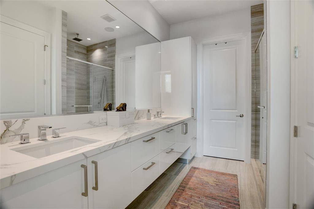 The primary en-suite features dual sinks, a separate shower with a rain showerhead, and a private water closet. The door leads to a generously sized walk-in closet, offering both function and luxury.