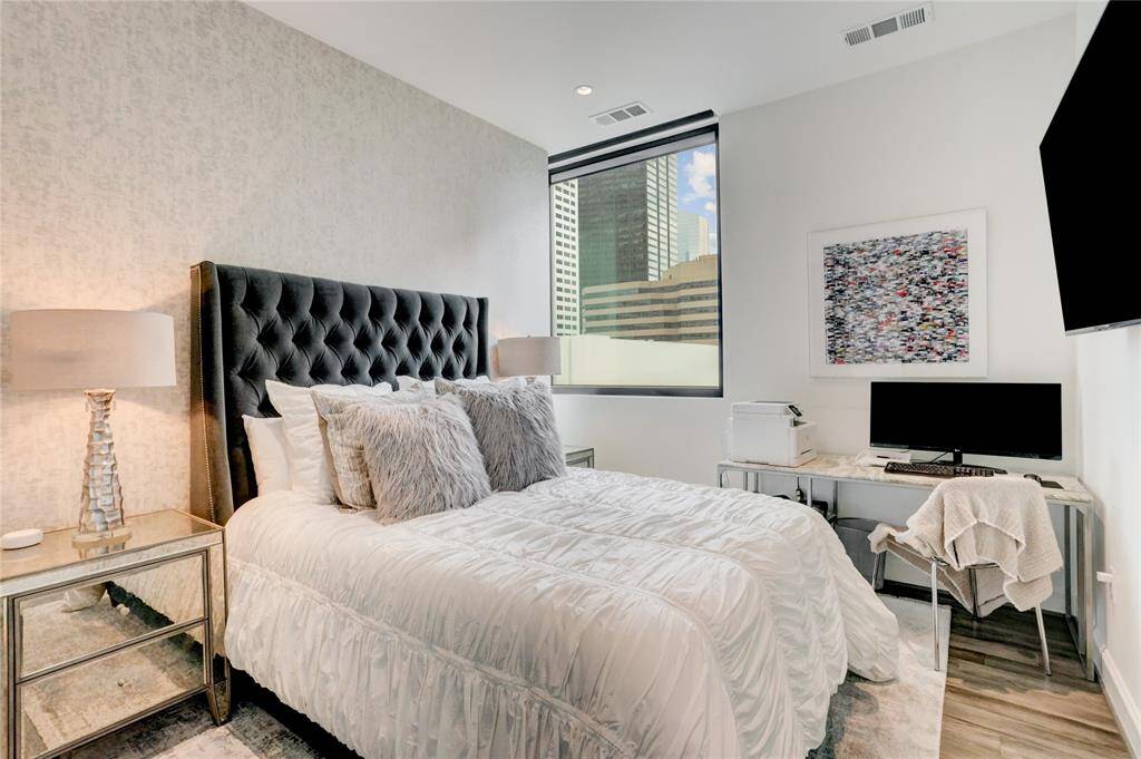 The second bedroom is spacious and includes its own en-suite bathroom. A large window fills the room with natural light, creating a bright and comfortable space.