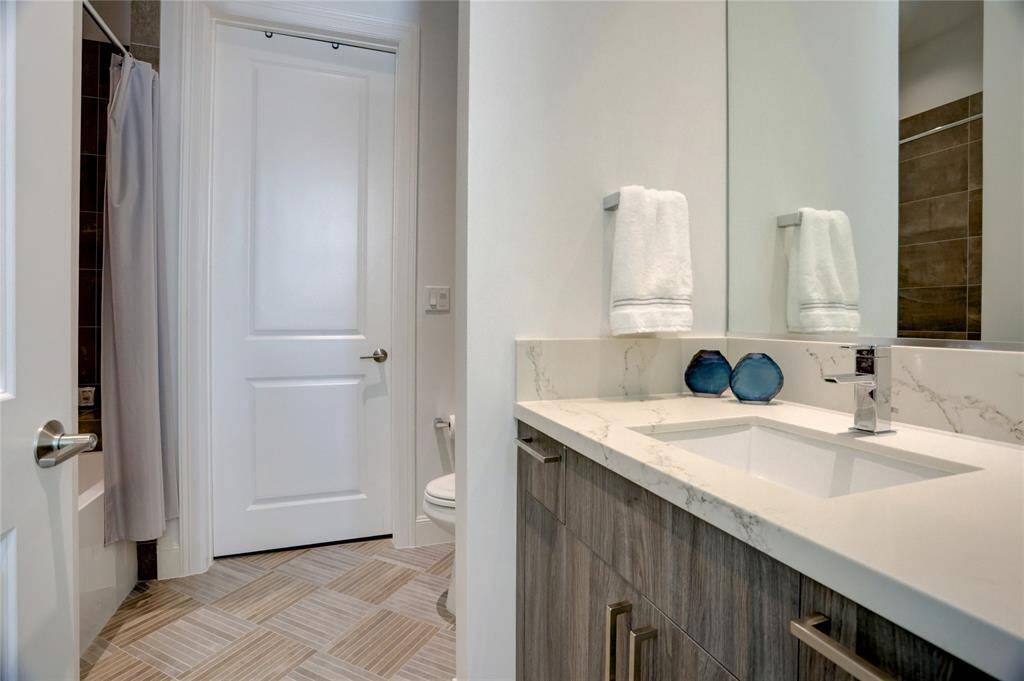 The second en-suite bathroom features a sleek vanity, ample storage, and a combination tub and shower. The door leads to a walk-in closet for added convenience.