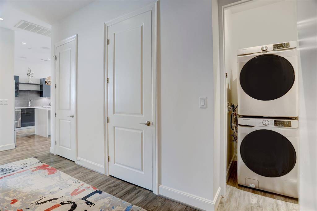 Tucked away in the entryway, the stackable washer and dryer are concealed behind a sleek push-door that blends seamlessly into the wall. Both appliances convey with the sale.
