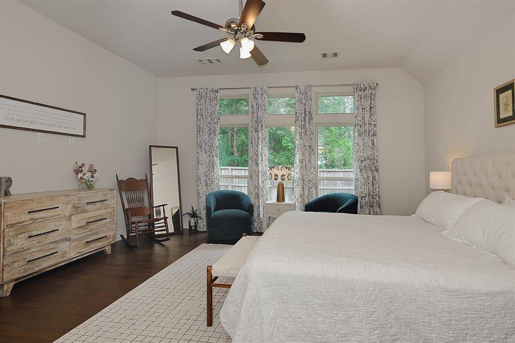 Wood look tile floors, a ceiling fan and neutral colors complete the primaryt bedroom
