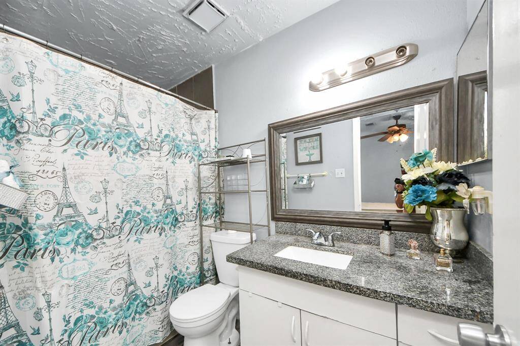This primary bathroom features a modern design with a granite countertop, and large framed mirror.