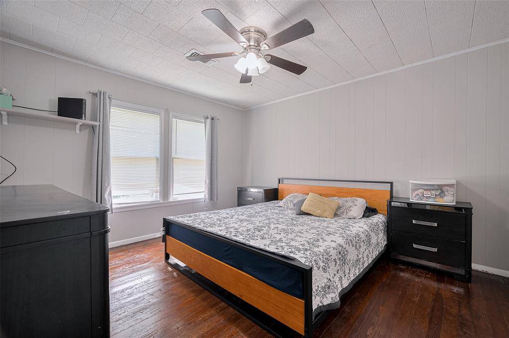 The primary bedroom offers peaceful retreat vibes with wood floors, a large window, and a ceiling fan overhead to keep the space cool.