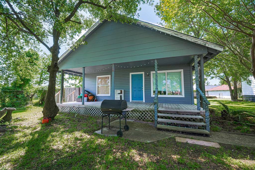 The first house greets you with a cheerful blue façade and an inviting front porch that spans the entire width—ideal for morning coffee or late afternoon unwinding beneath the trees.