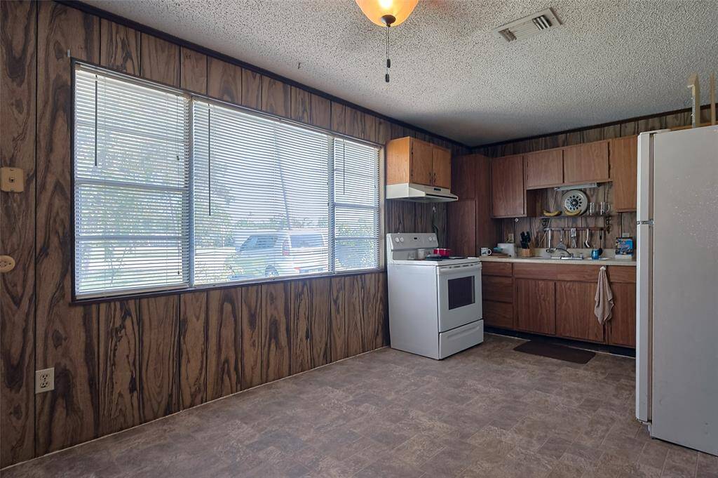 The kitchen's spacious layout can easily accommodate a dining space. A wide window brings in natural light and frames views of the greenery just outside.