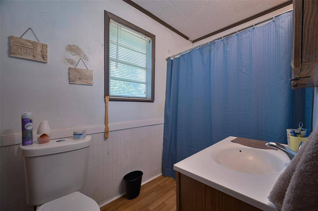 The home’s full bathroom features a vanity, a sunny window, and functional simplicity.
